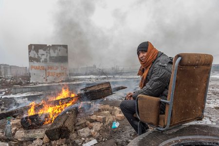 Barracks of Belgrade, a refugee man tries to keep warm