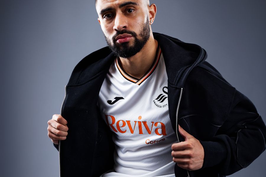 Footballer Josh Ginnelly poses in a home shirt during a studio shoot, for the 2024-2025 Championship football season, at the Swansea City AFC club shop, Swansea, Wales, UK